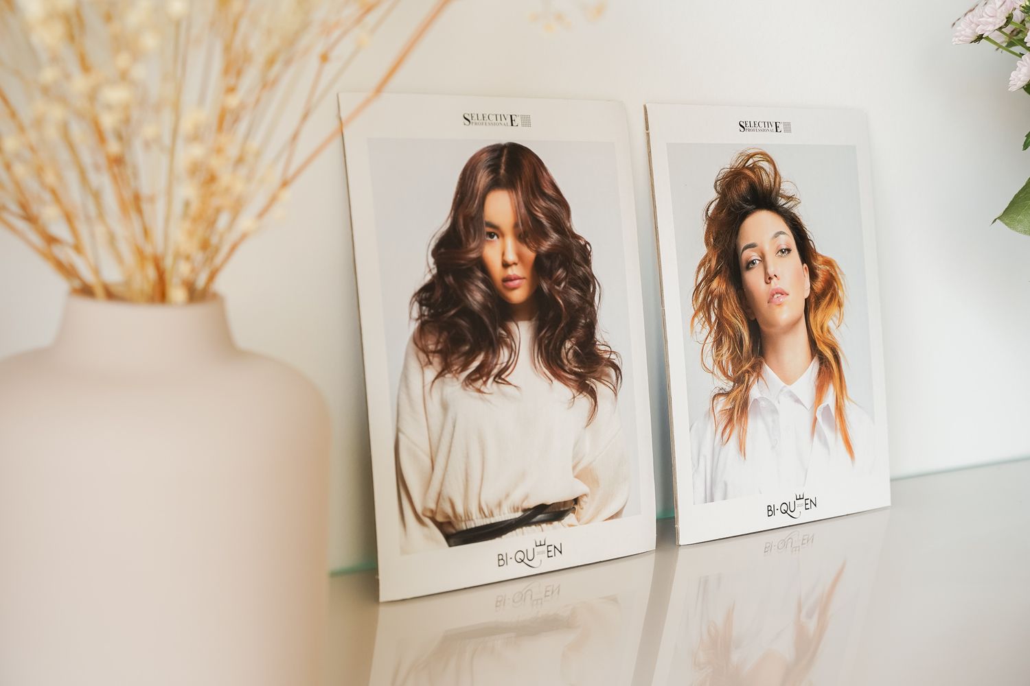 Two fashion photography posters showing hairstyle portraits mounted on white wall.