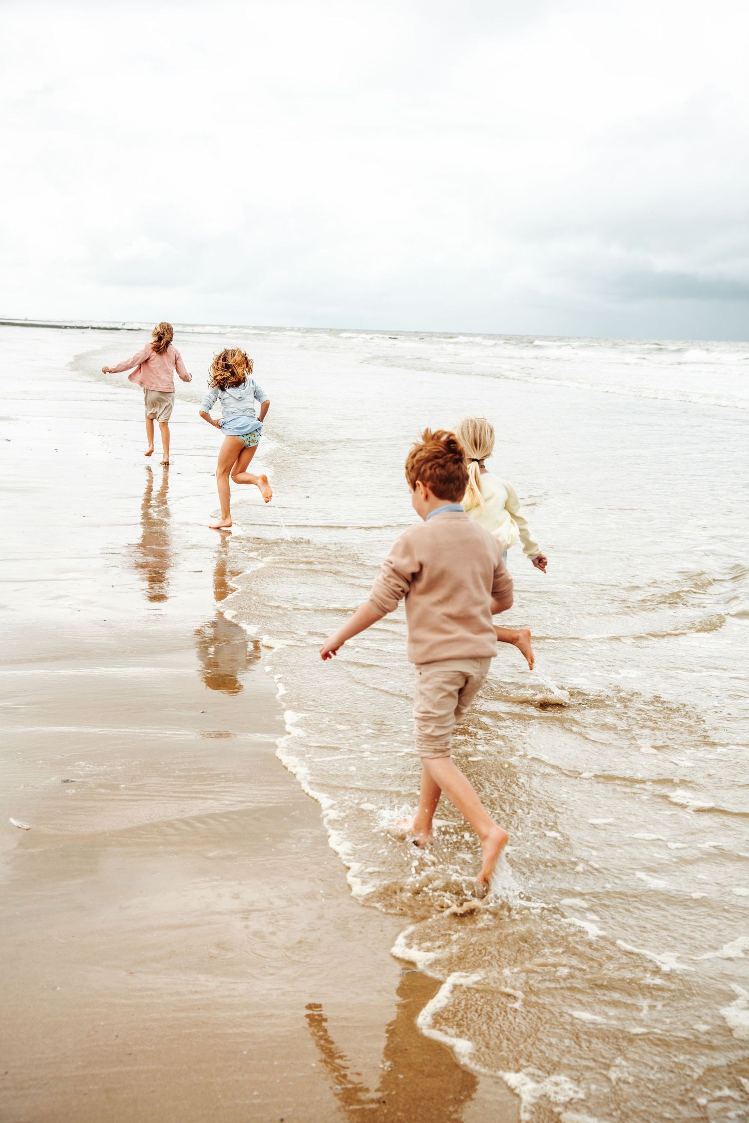 Children splashing and playing in shallow ocean waves at the beach.