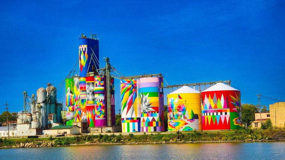 Colorfully painted industrial storage silos with vibrant murals create an artistic display along the waterfront Saginaw Michigan.
