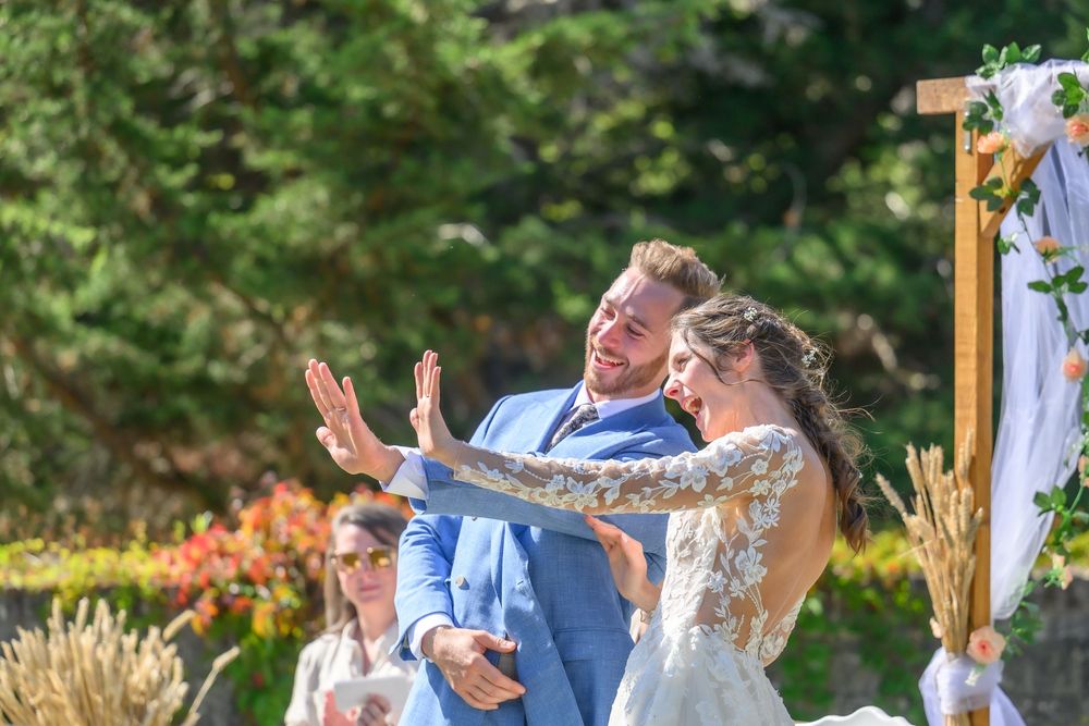 Happy couple dancing and laughing together outdoors in a garden setting during a celebration.