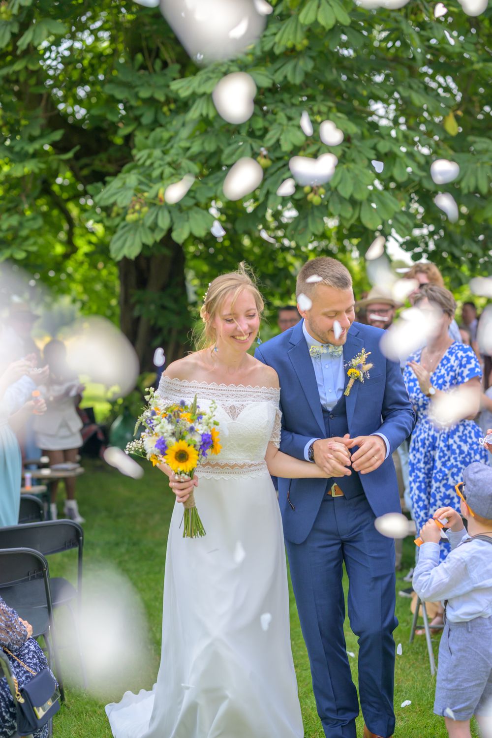 Garden wedding ceremony with bokeh effect and sunlight filtering through green trees.