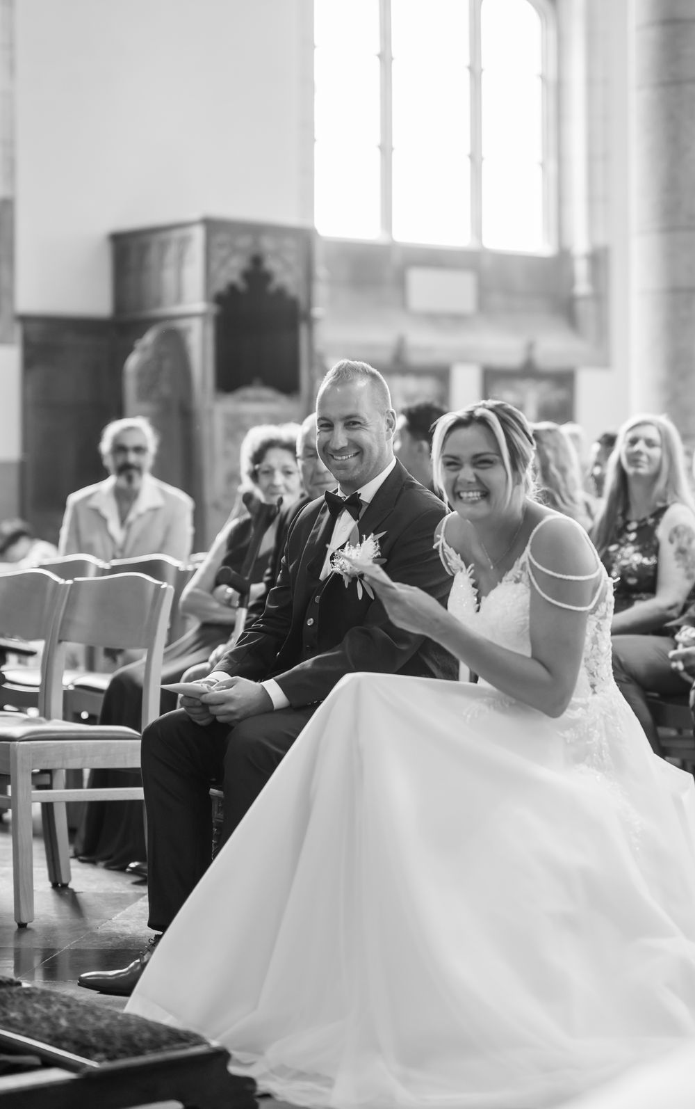 Black and white photograph of joyful moments during wedding ceremony in historic church setting.