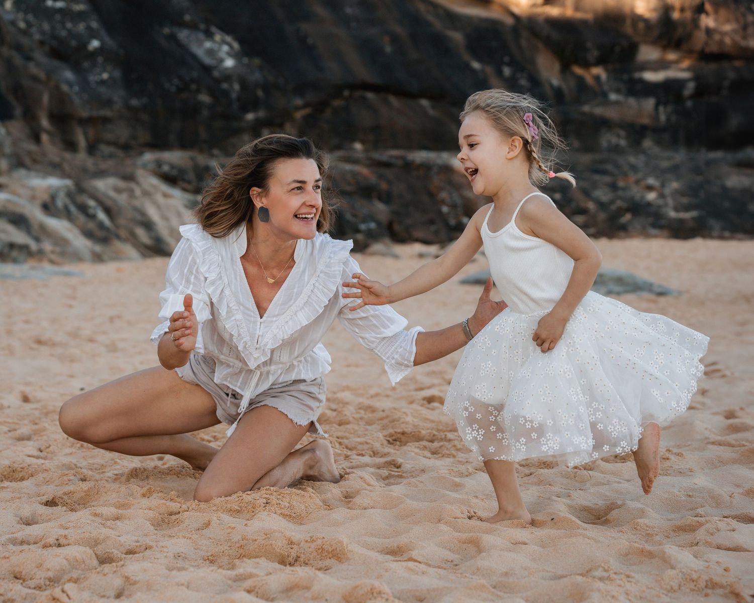 mom-and-daughter-plays-in-the-sand-at-the-norther-beaches-during-a-family-photoshoot