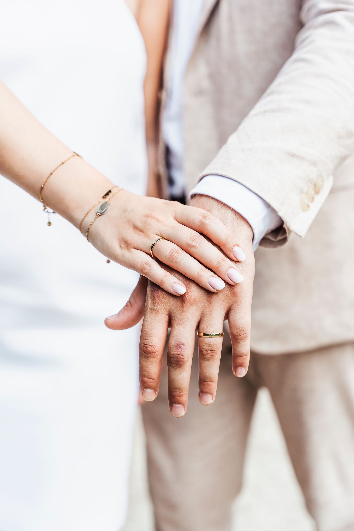 Close-up of hands with wedding rings and delicate bracelets.