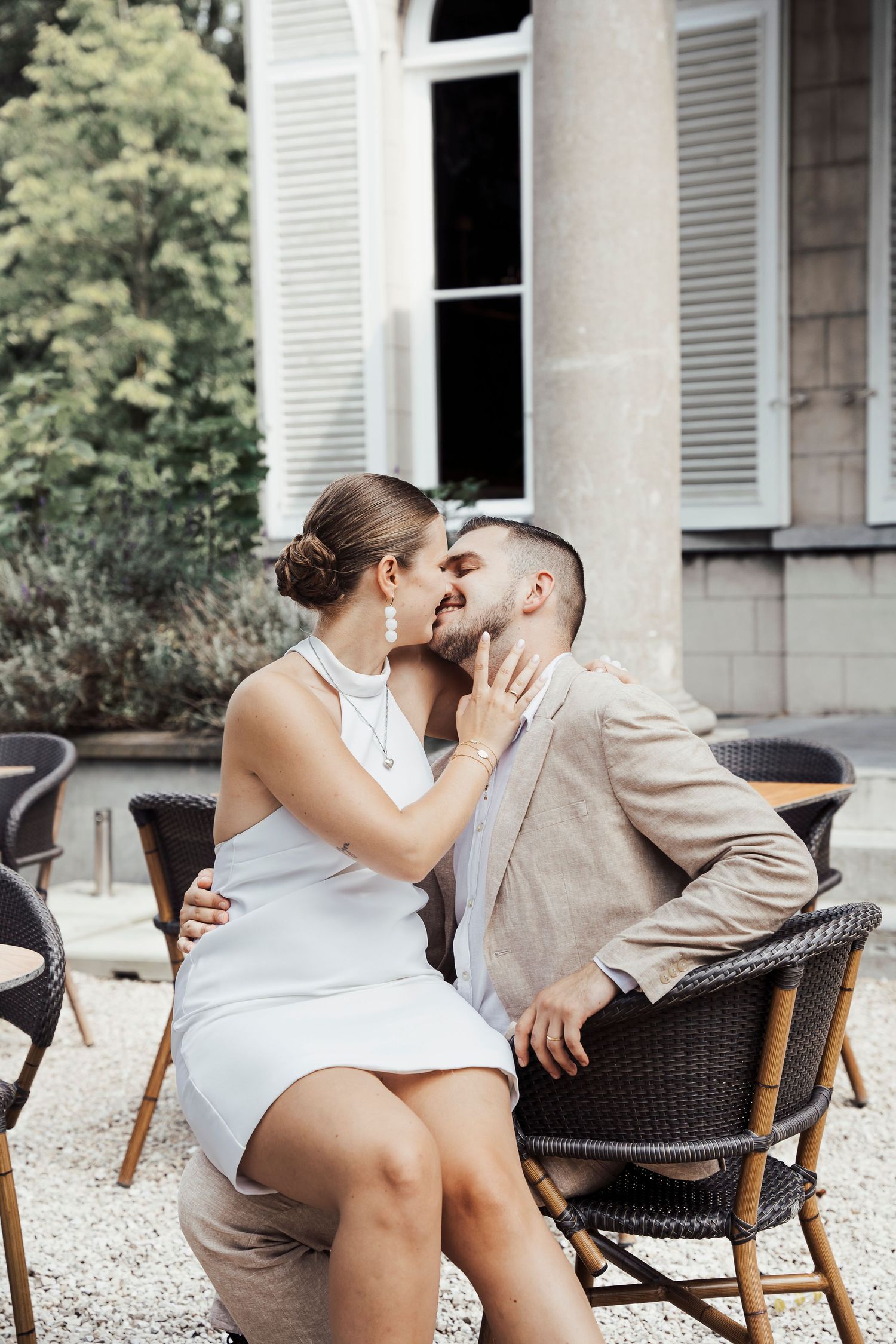 Intimate moment shared between couple on wicker chair outdoors.