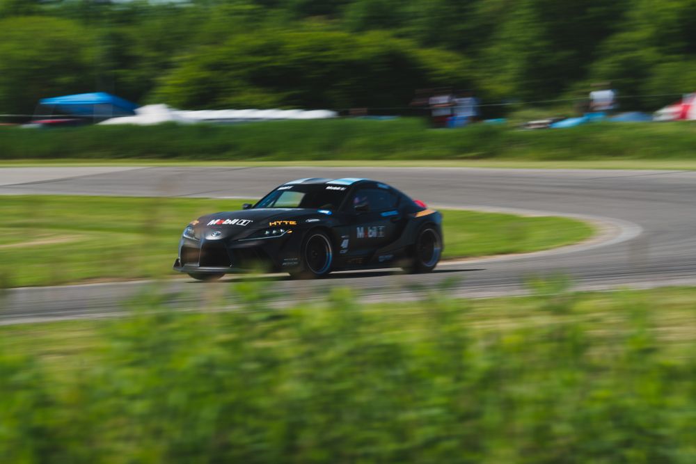 Black sports car racing through corner on race track with motion blur.