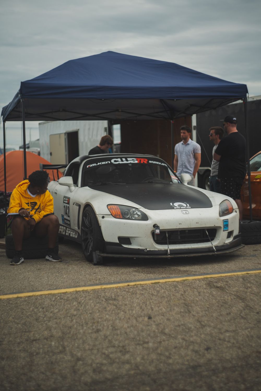 White Honda S2000 race car parked under blue tent at motorsport event.