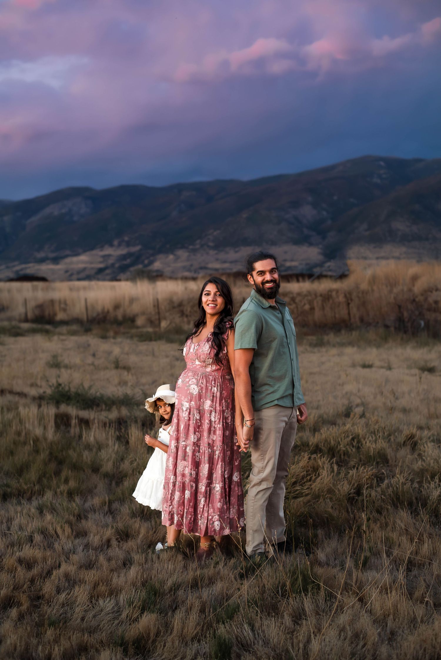 expecting couple standing together in an open field during a maternity photography session in Utah