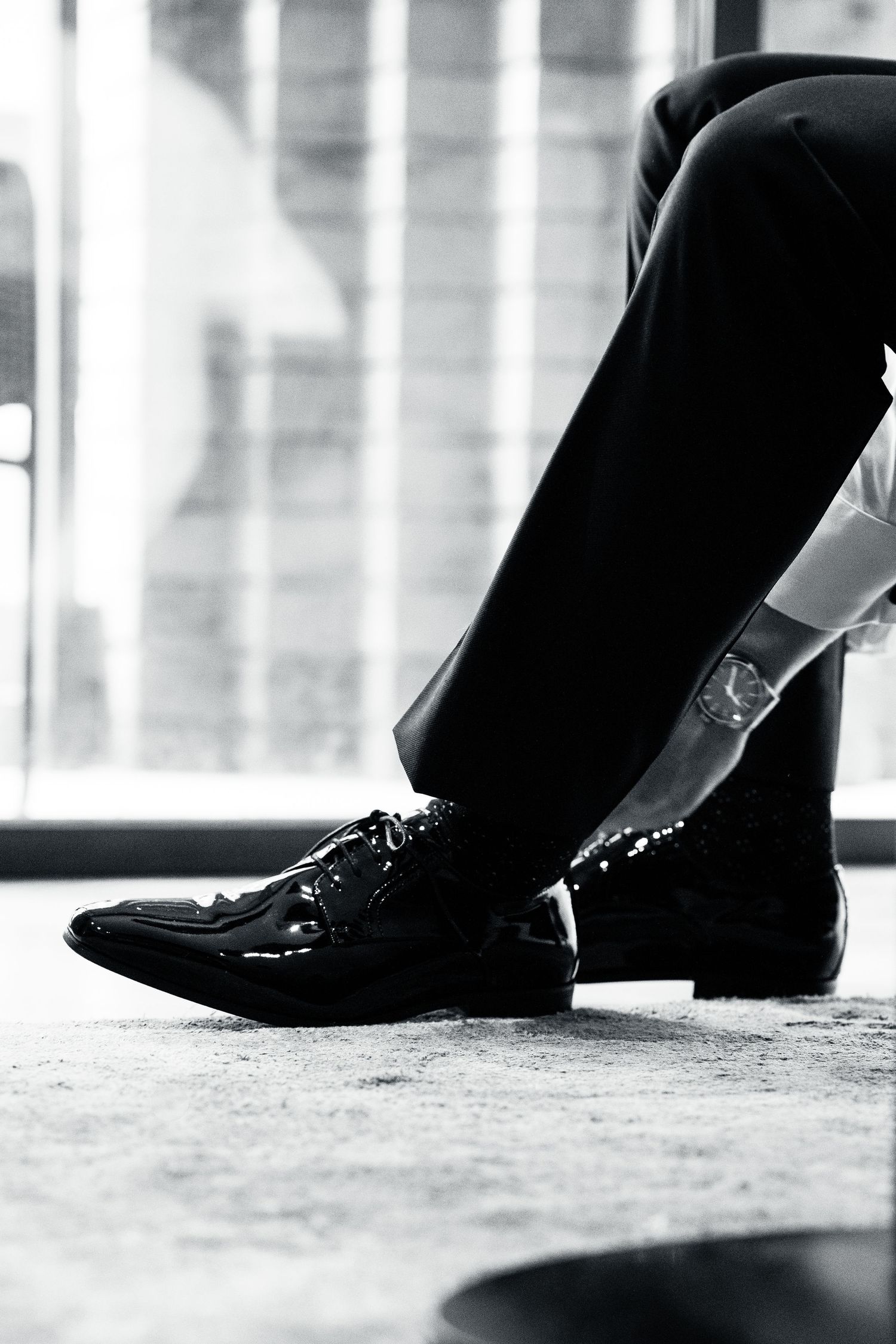 Close-up of shiny black formal dress shoes and pants in black and white.