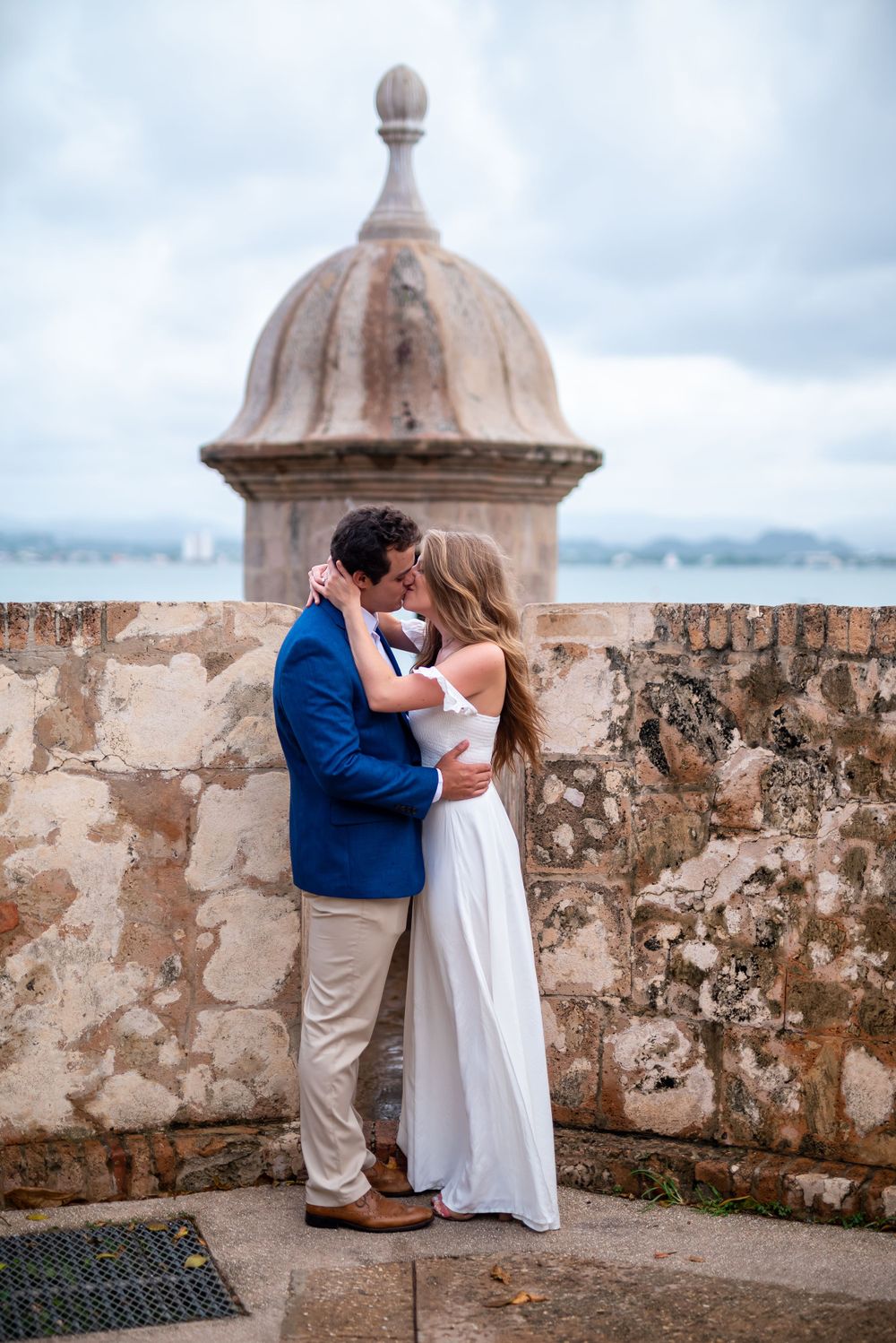 A romantic embrace by an ancient stone turret with ocean views.