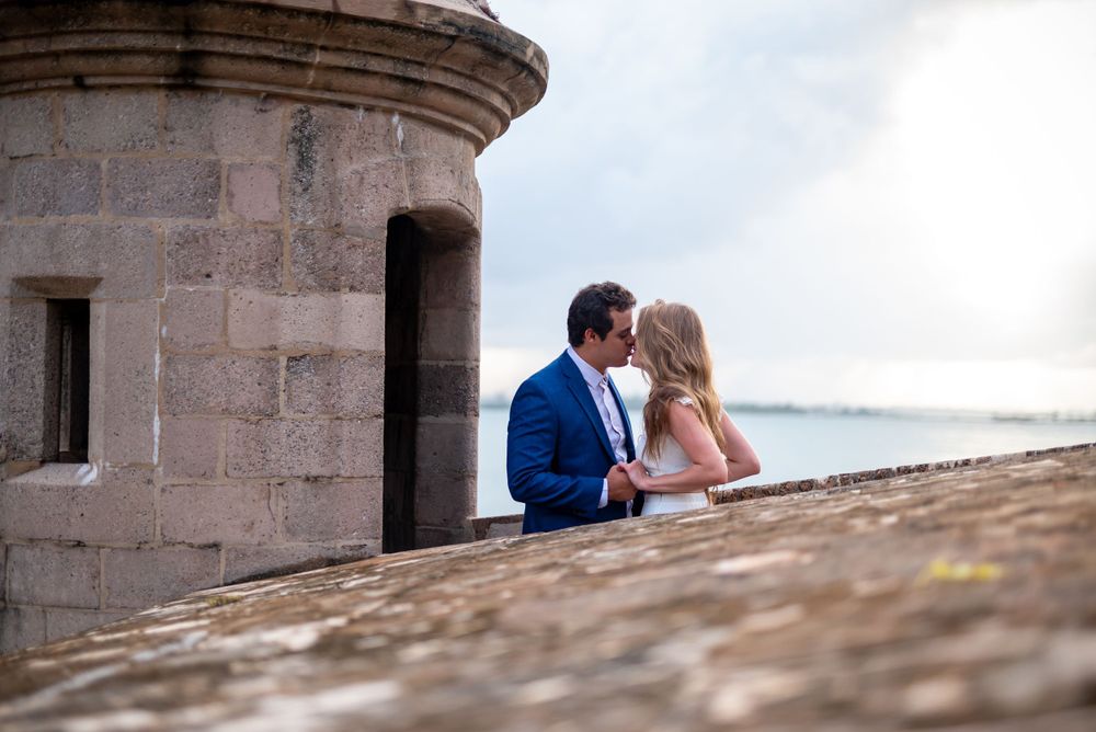 A couple shares an intimate moment at a historic stone fort overlooking the sea.