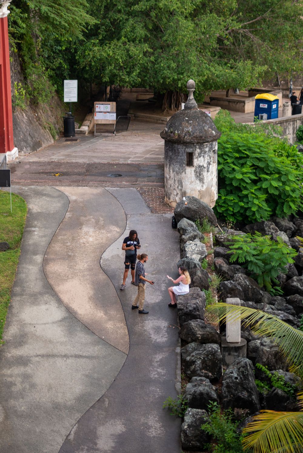 A curved stone pathway leads through a tropical garden with an ornate pillar and lush greenery.