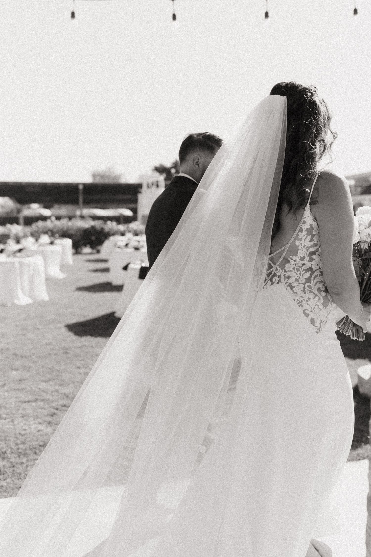 couple in wedding attire walking away with backs turned and having a private moment after getting married.