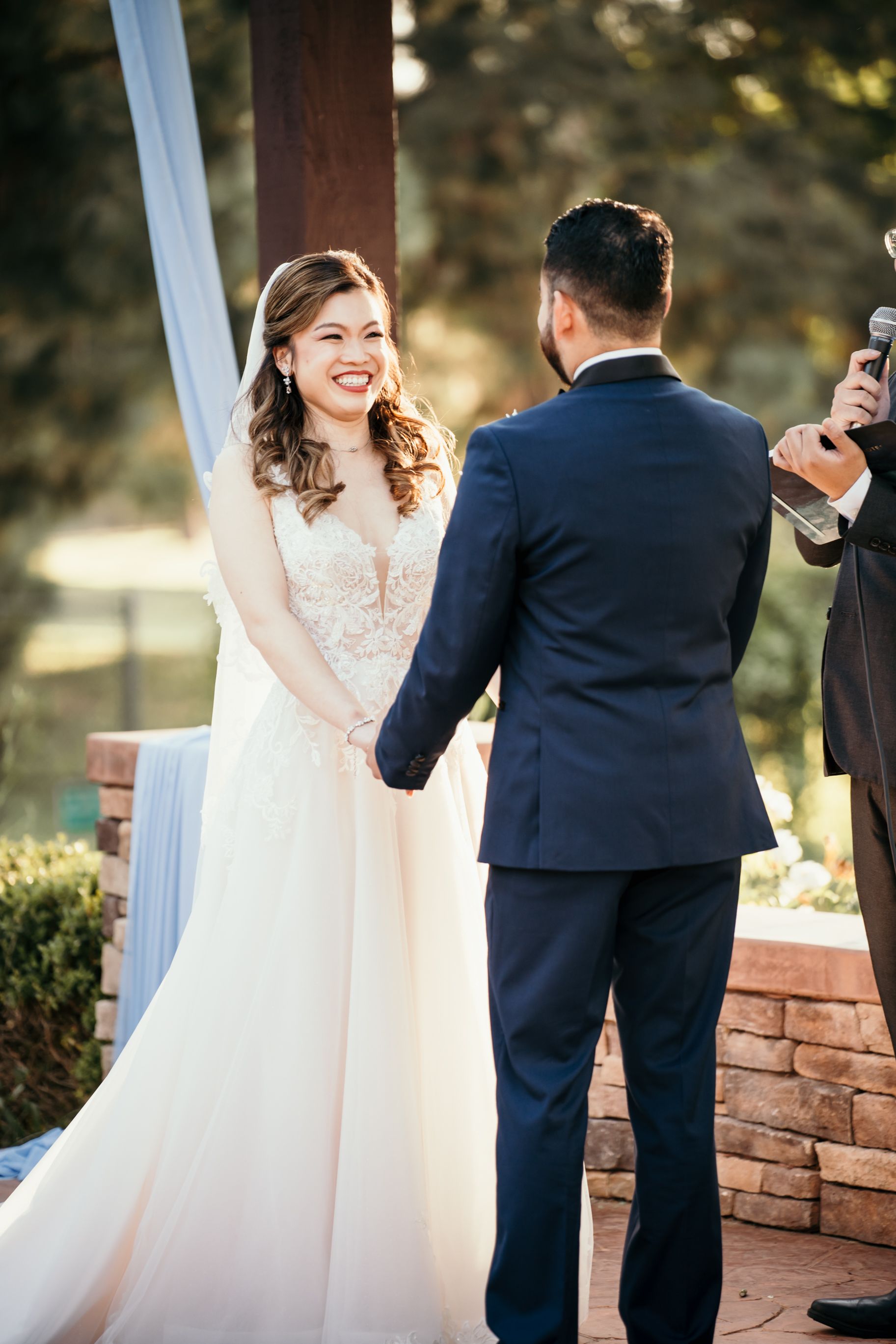 Tender moment during wedding ceremony on a brick-lined outdoor pavilion.