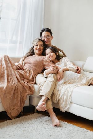 Family relaxing together on white sofa in cozy living room with natural light.