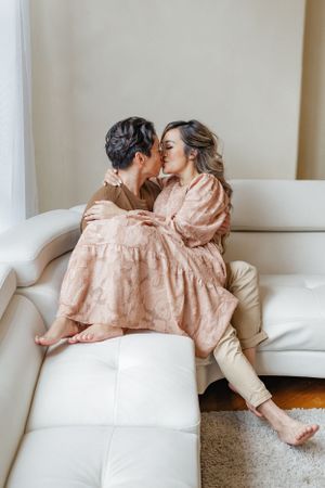 Intimate moment captured on white sofa in minimalist living room setting.