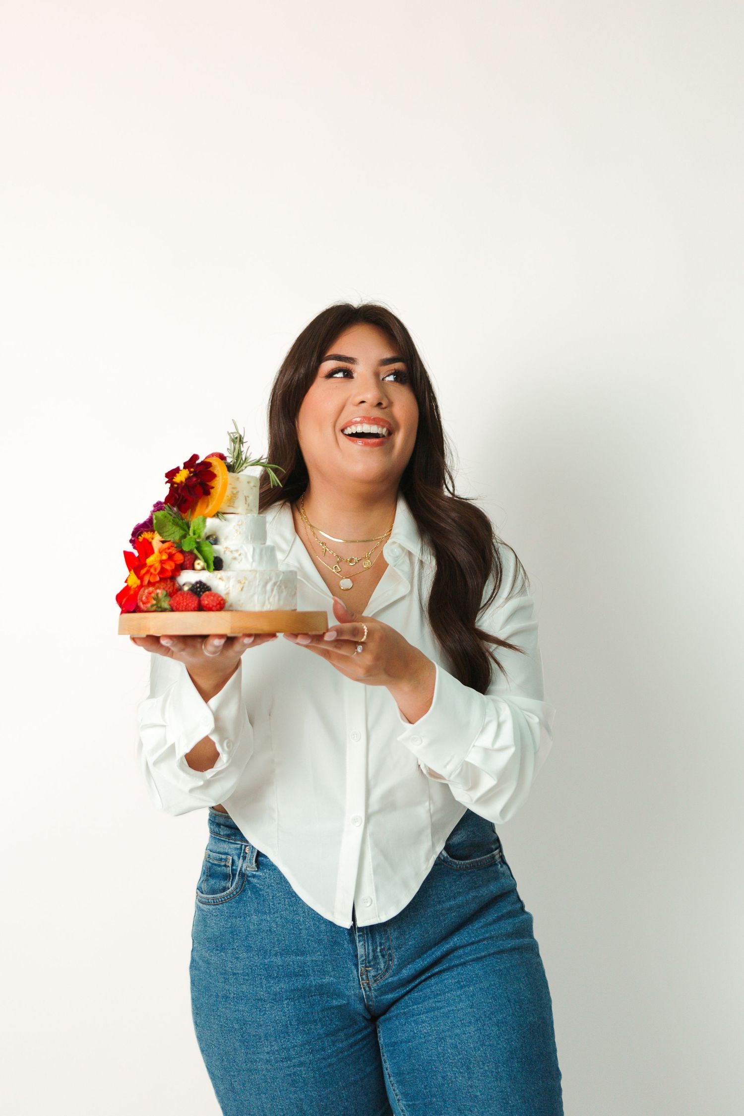 Woman in casual attire joyfully holding a plate with vibrant flowers and decor.