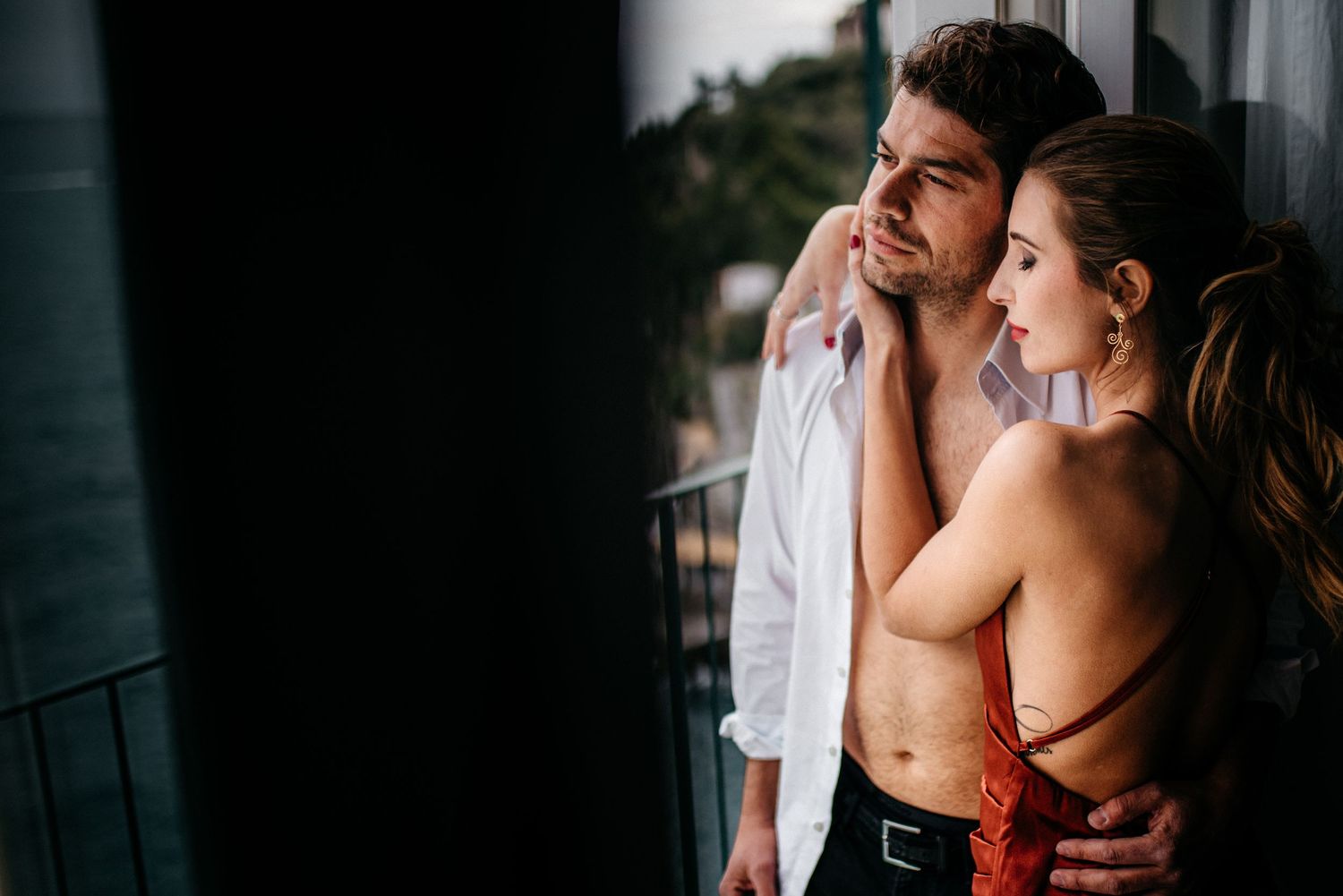 A couple cuddling together on a balcony in Positano, Italy.