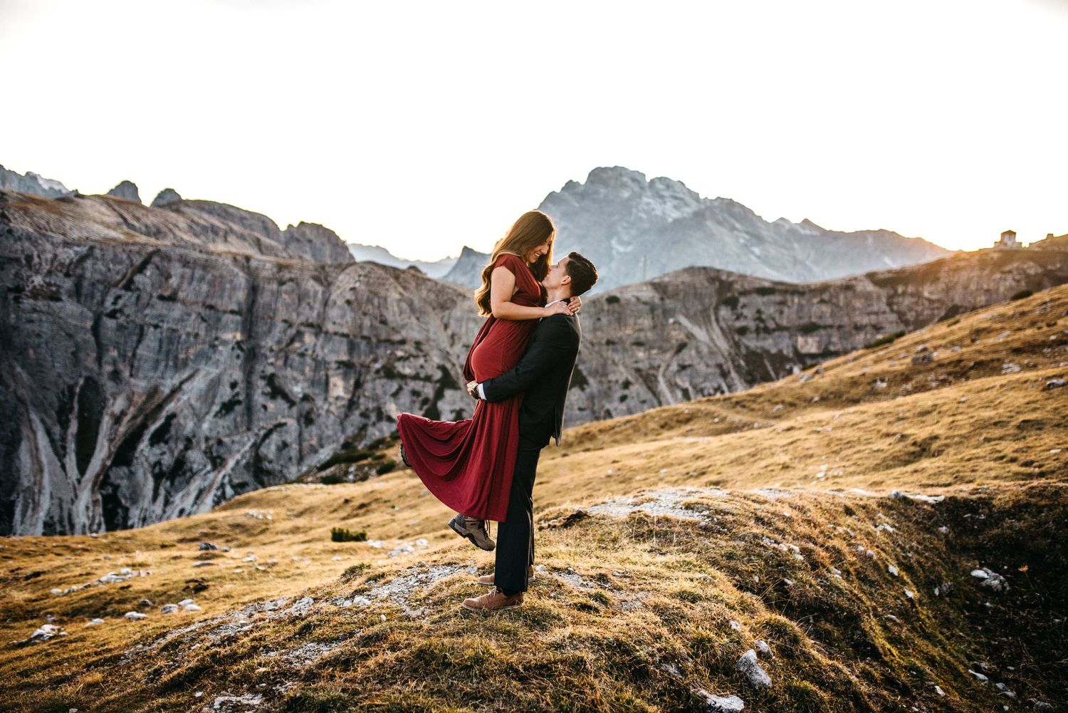 Husband picks wife up at sunset in the mountains of Tre Cime, Italy.