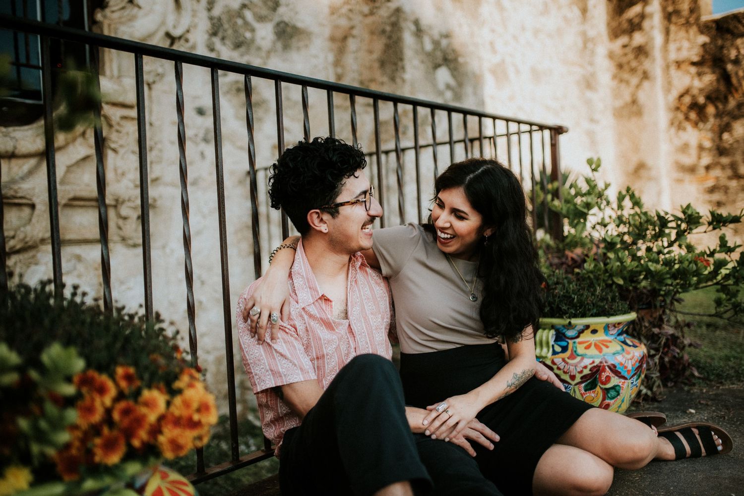 A couple sharing an intimate laugh as they sit outside the mission in San Antonio, Texas for a portrait.