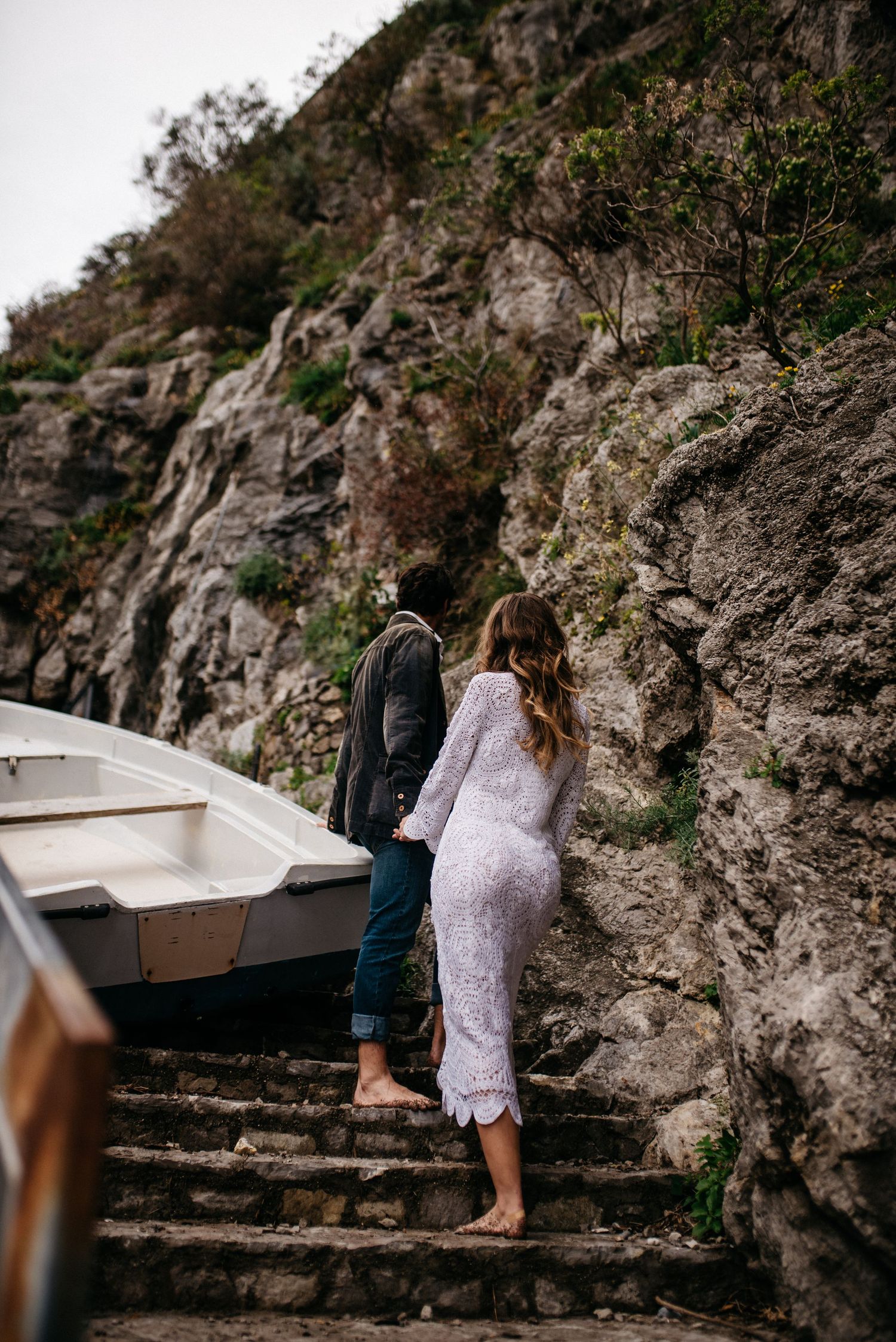 A couple walking up the stairs in Positano, Italy passing a boat.