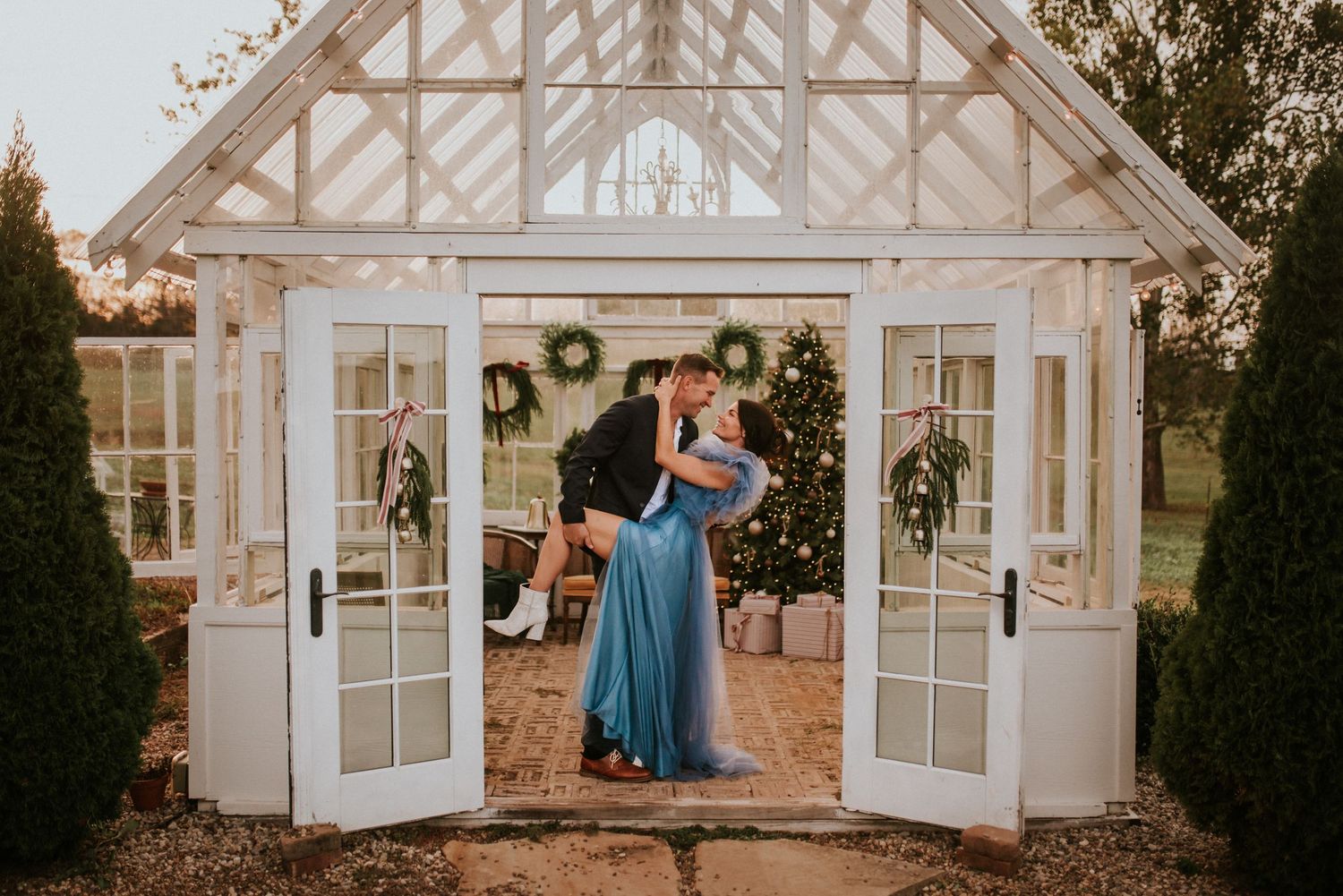 A couple in a Christmas decorated greenhouse studio dipping during sunset in Tennessee.