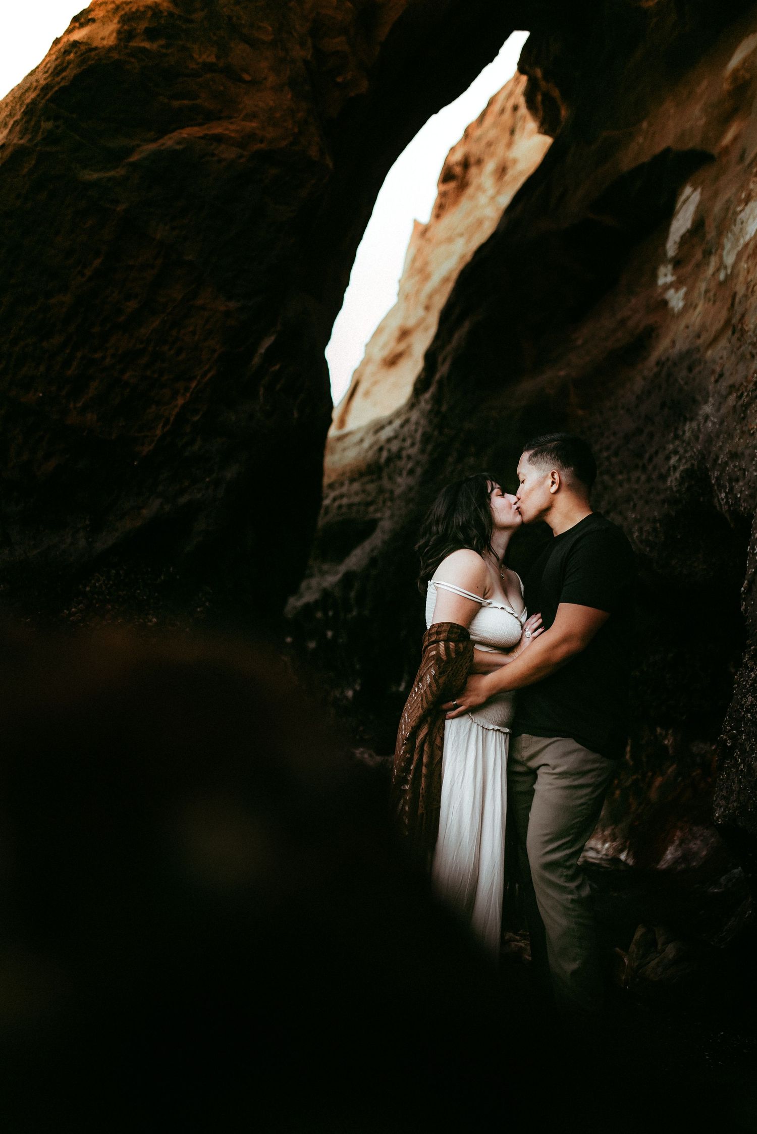 Couple kissing in the cave like formations of Pacific City, Oregon.