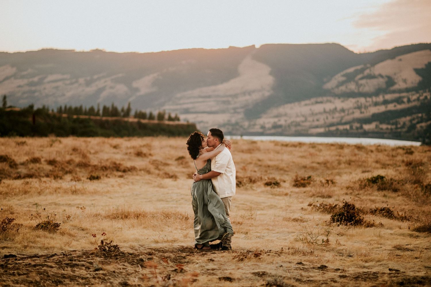 A couple embracing during sunset with golden tones of sunset in the gorge in Oregon.