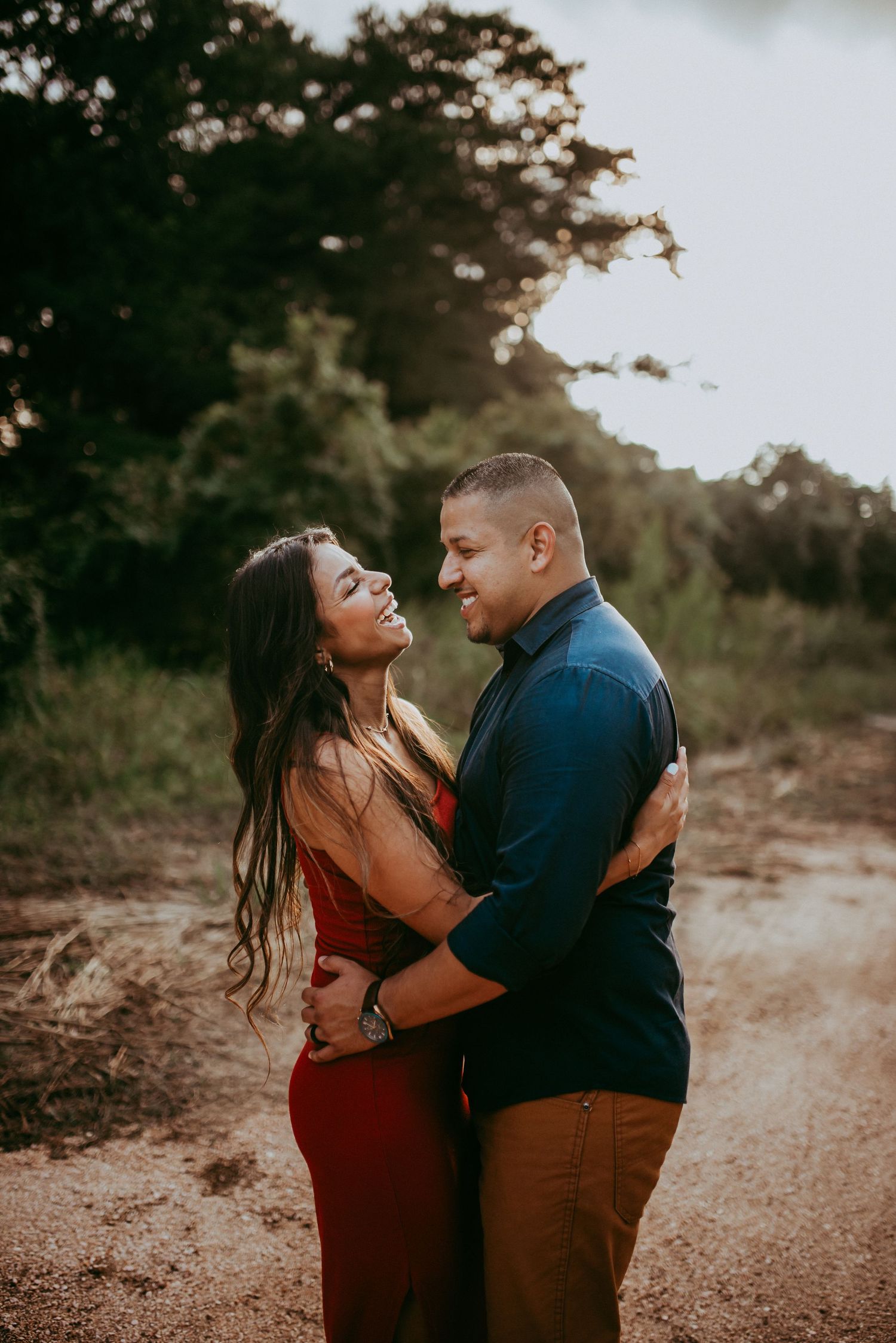 Couple laughing as they hold each other at sunset in New Braunfels, Texas.