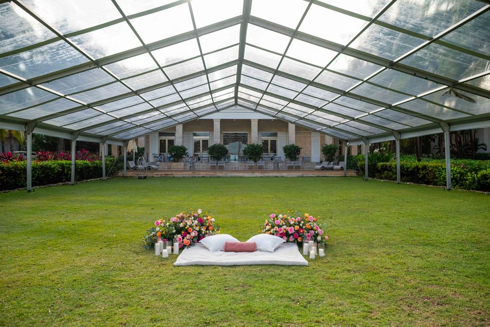 Wedding venue with clear tent covering a white lounge area decorated with flowers.