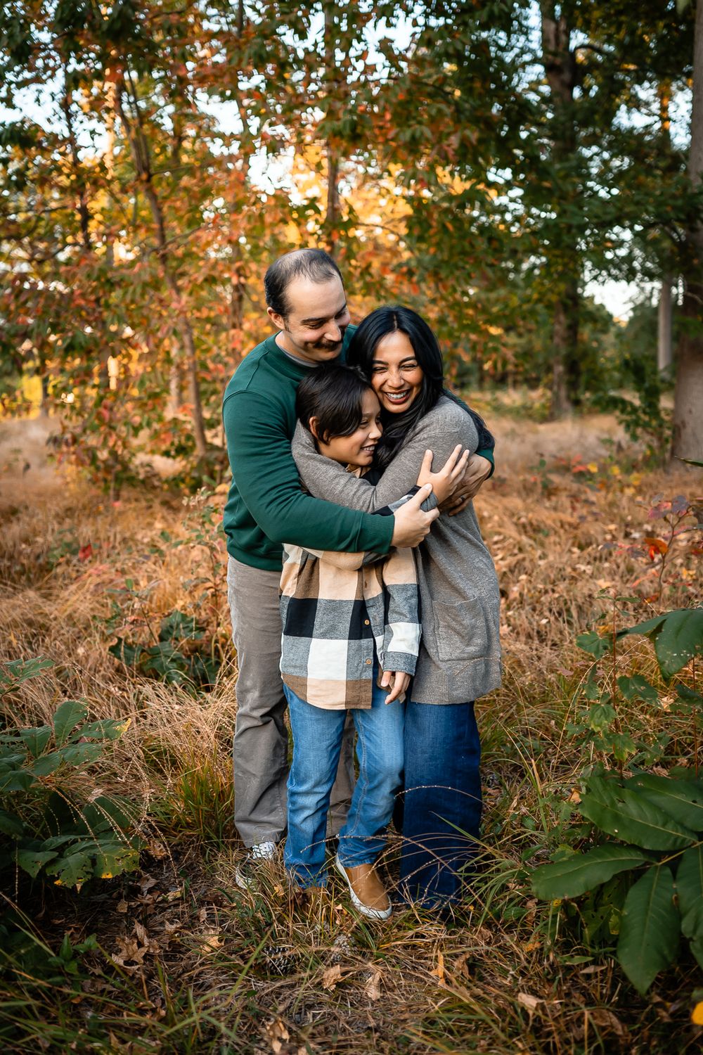 Loving family embrace captured in autumn forest setting with warm lighting.
