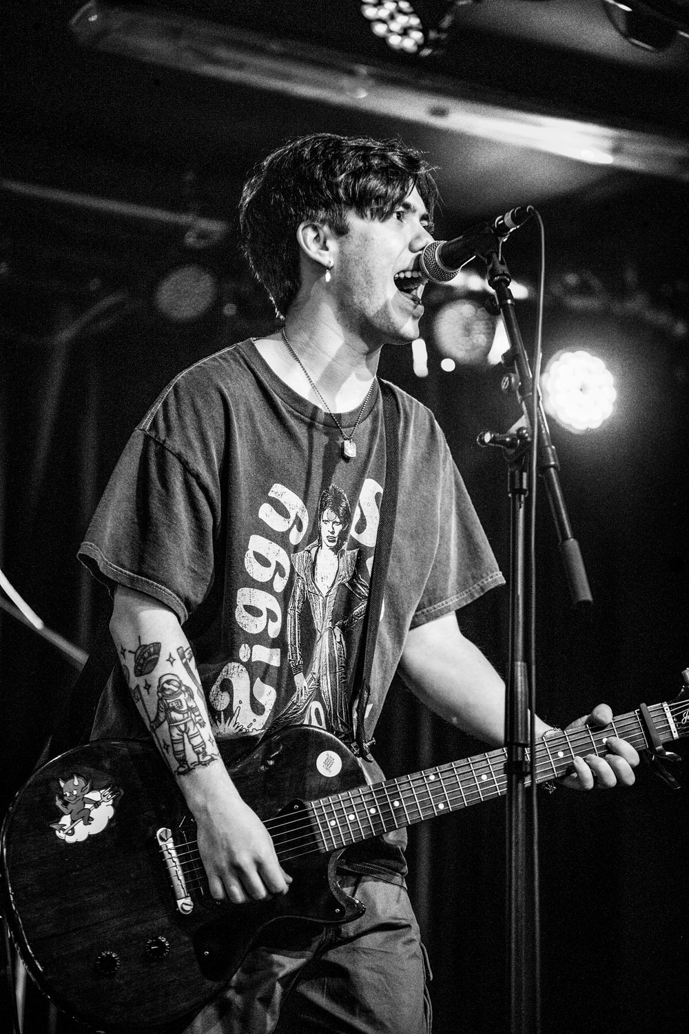 Event photography black and white image of a man playing guitar while singing on a stage. Captured in Newbridge, South Wales