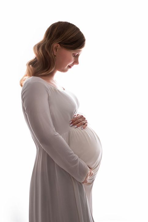 backlit portrait of expecting mom in white dress in studio maternity session Baltimore, Ontario*