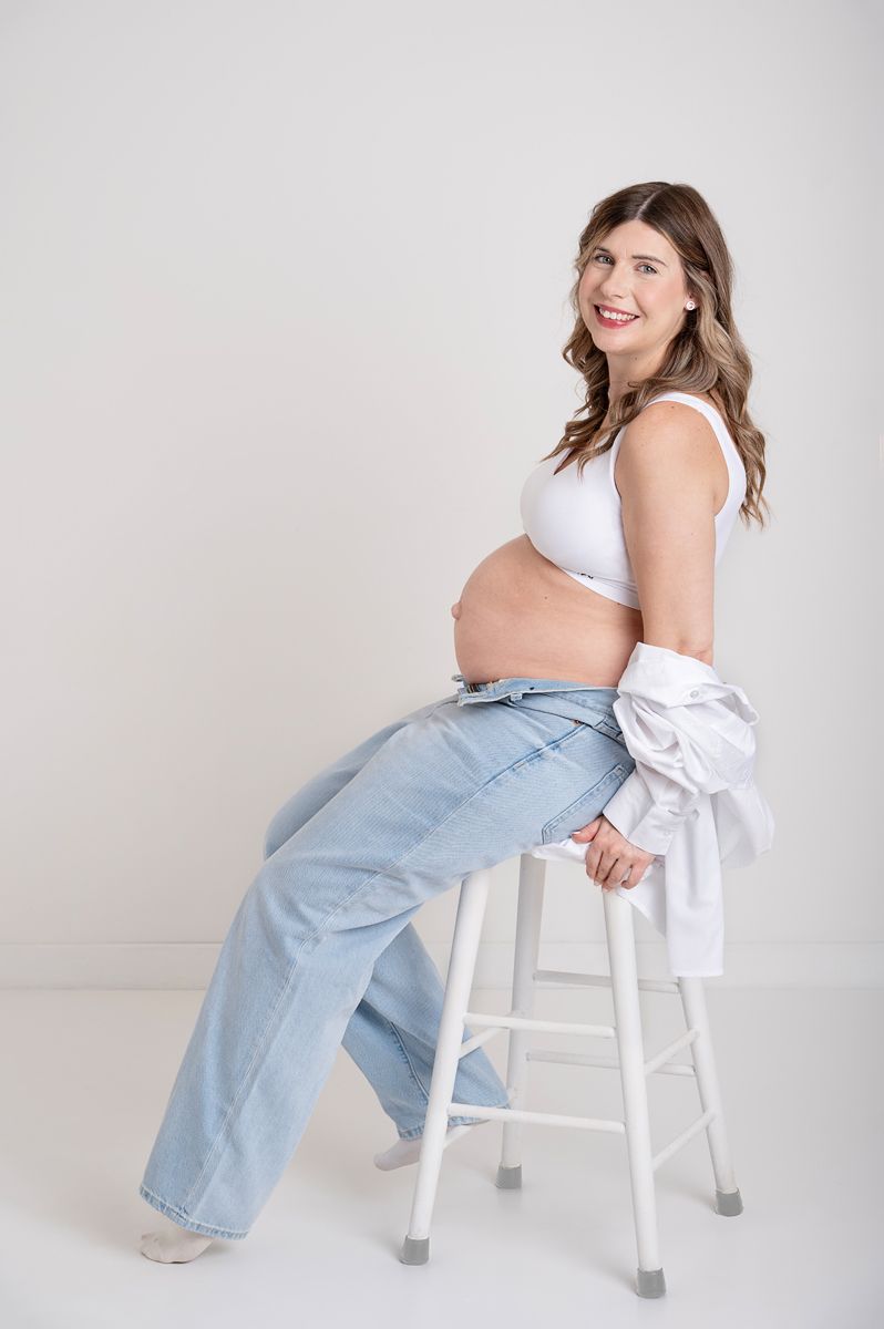 in studio maternity photography session of expecting mom posed on white stool in Baltimore, Ontario*