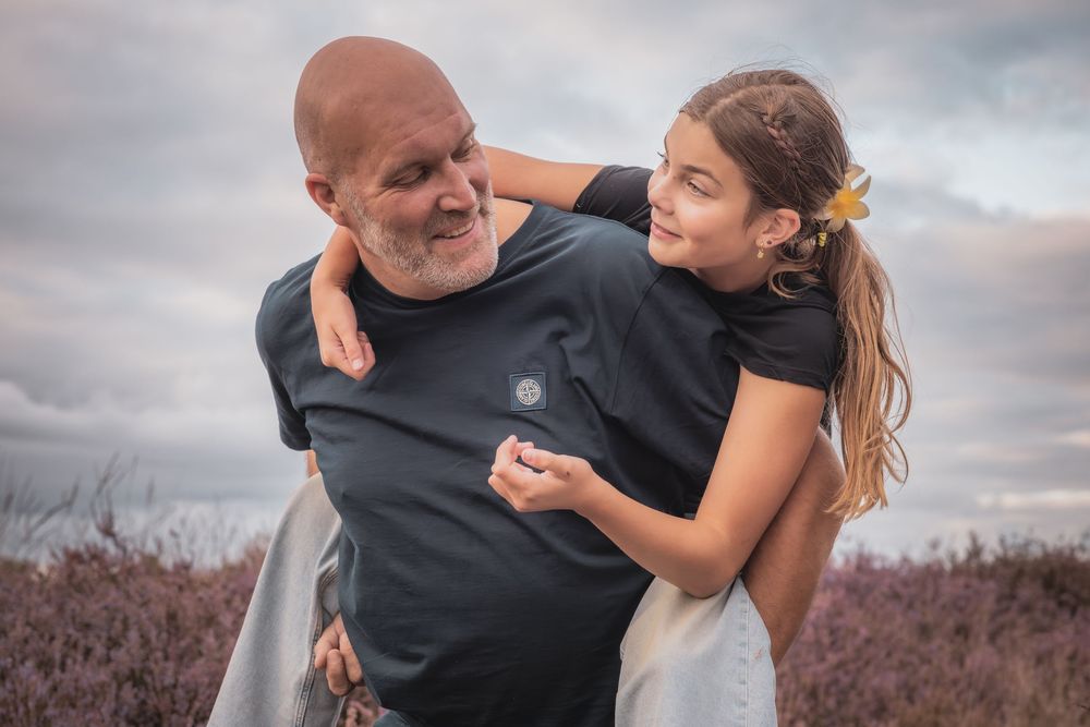 A parent and child share tender moments together against a cloudy sky background in a series of candid shots.