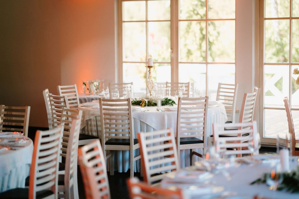 Elegant reception venue with natural light streaming through large windows and white chairs.