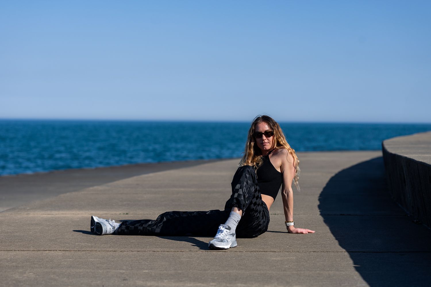 Casual lifestyle photo of a person lounging on a concrete pier by a boy of water.