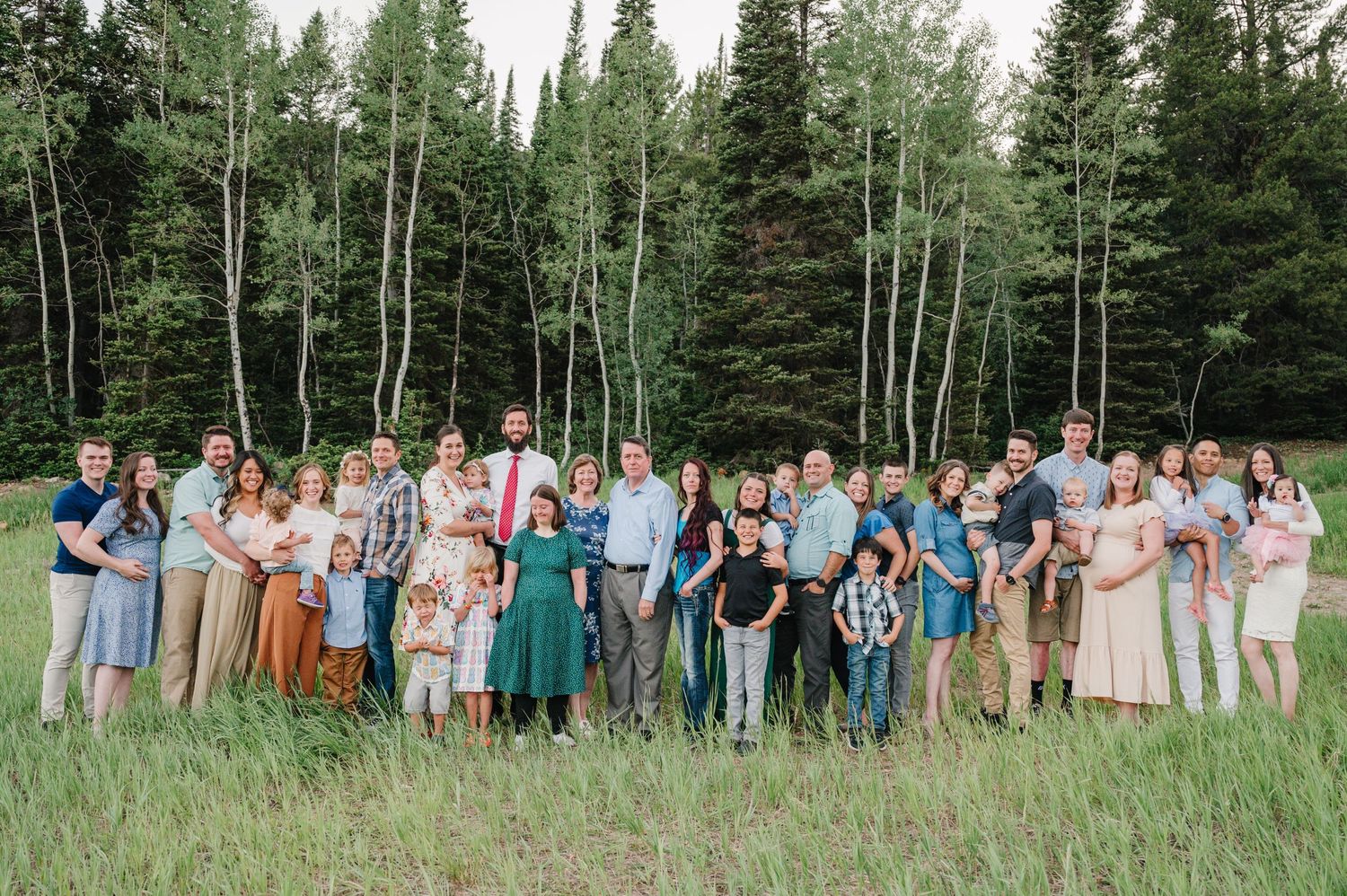 Large family group poses together in a mountain meadow surrounded by aspen and pine trees.