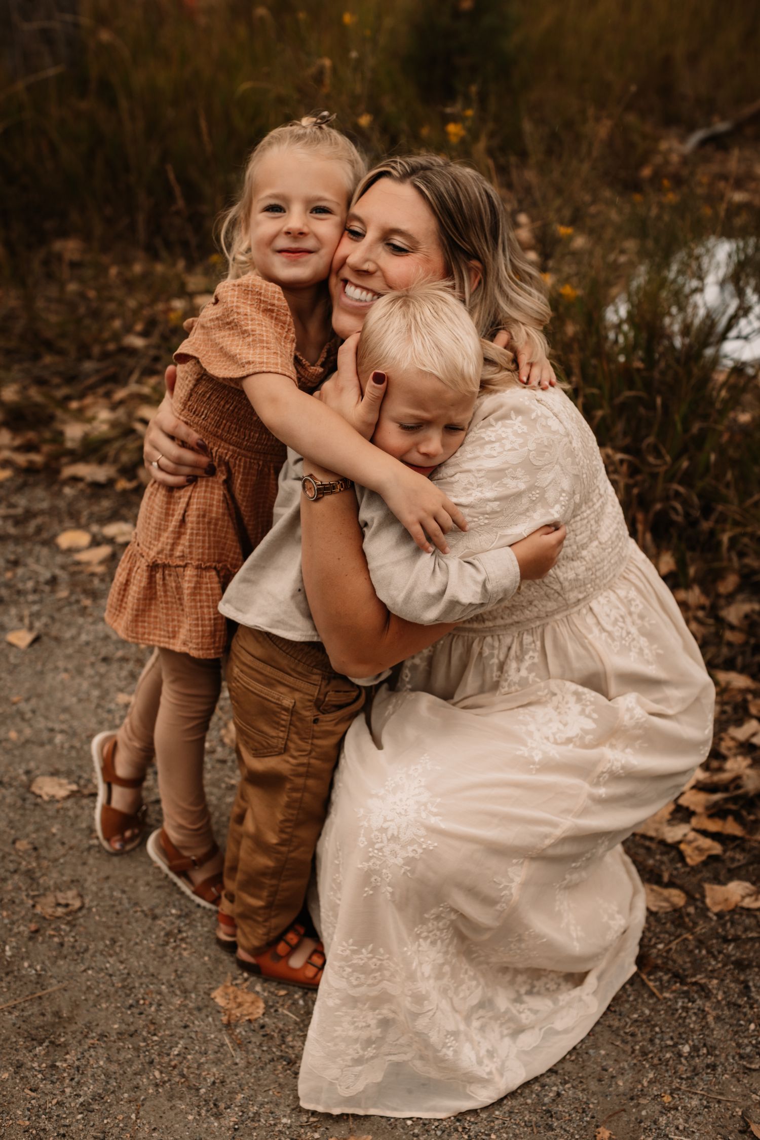 Two young children play in fallen autumn leaves while wearing vintage-style clothing.