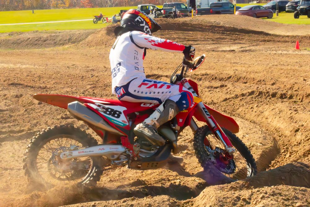 Motocross rider riding his bike with a cloud of dust in the background.
