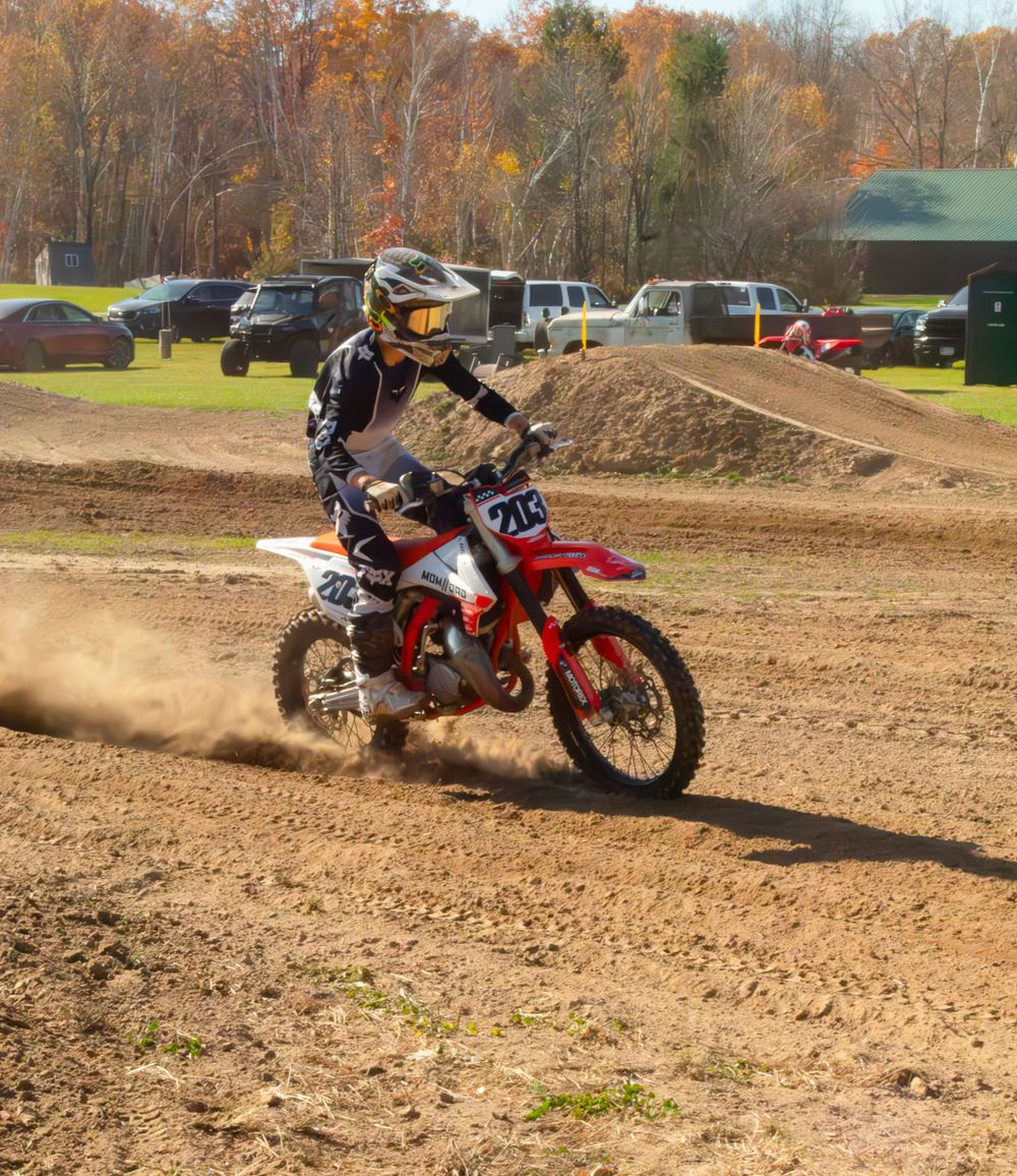 Motocross rider riding his bike with a cloud of dust in the background.