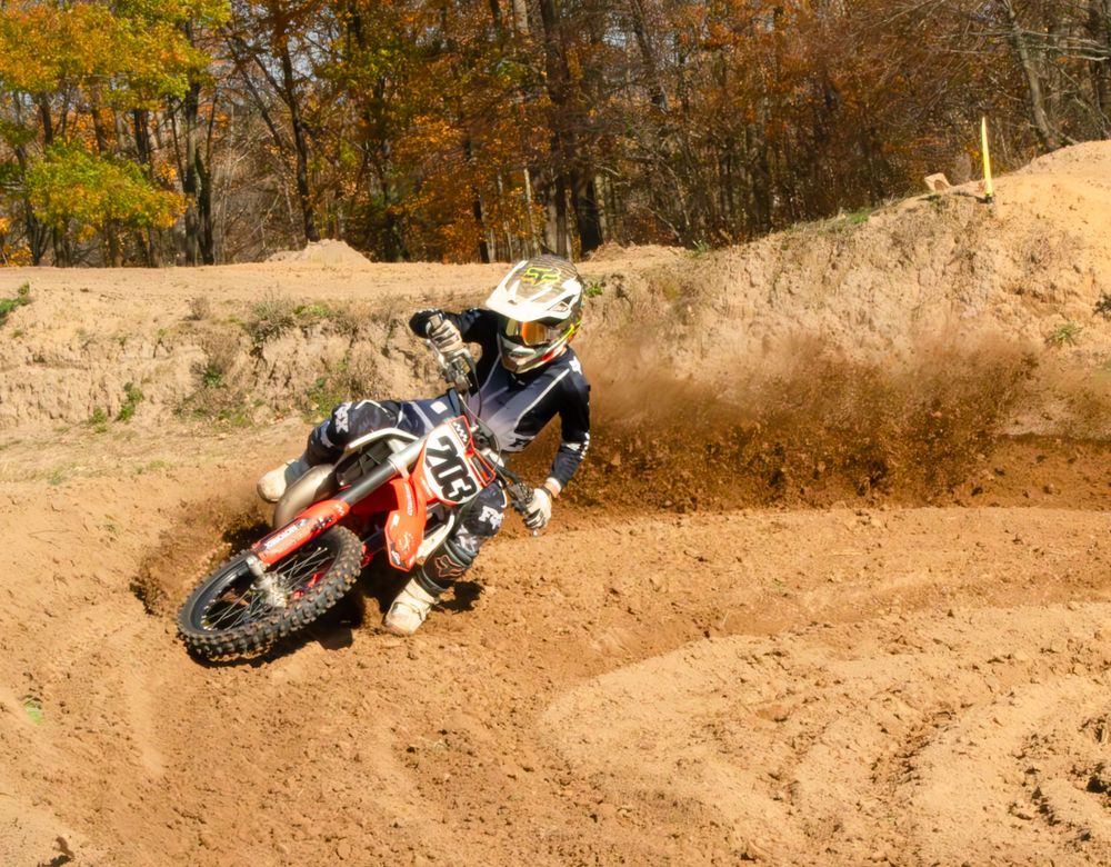 Motocross rider riding his bike with a cloud of dust in the background.