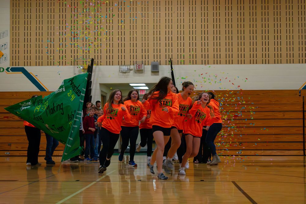 Prairie Farm Wisconsin Cross Country team 2024 running out into the gym excitedly with confetti raining down on them.