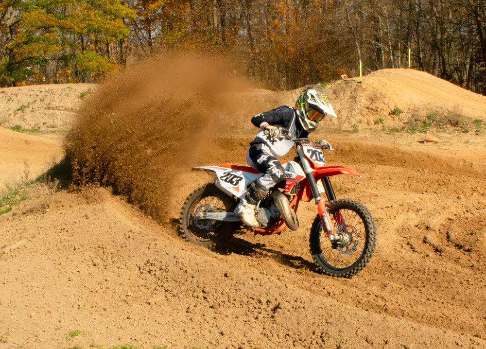 Motocross rider riding his bike with a cloud of dust in the background.