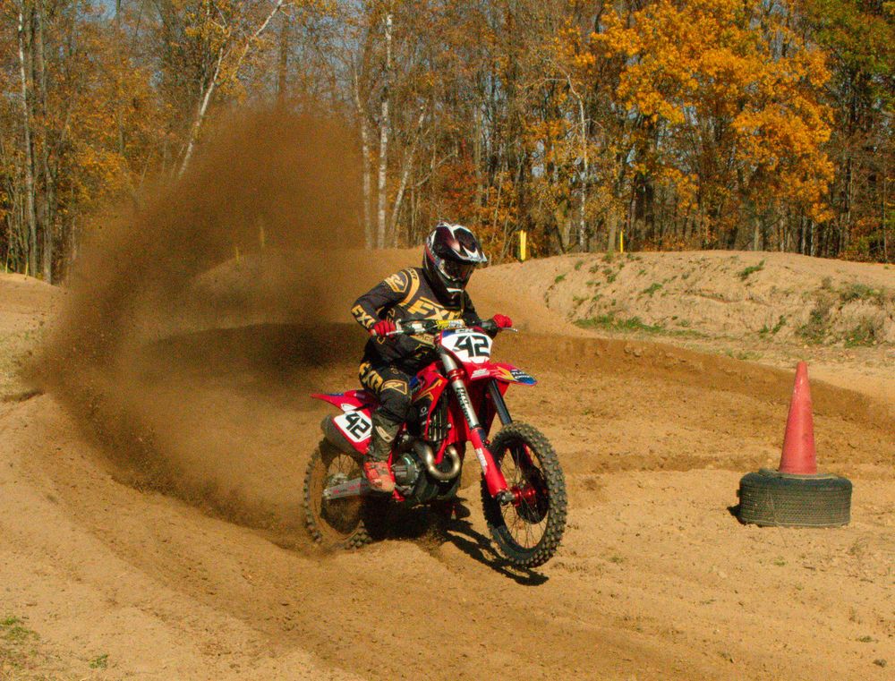 Motocross rider riding his bike with a cloud of dust in the background.