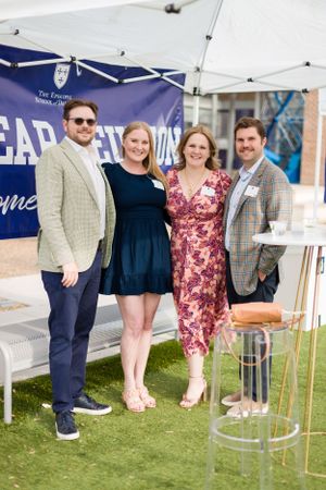 Group photo of four attendees at an outdoor event with LEAP banner and tent setup.