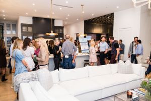 Elegant open concept living room with white sectional sofa and pendant lighting during a social gathering.
