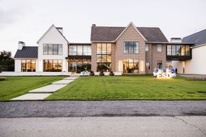 Modern luxury home exterior with landscaping illuminated at dusk.