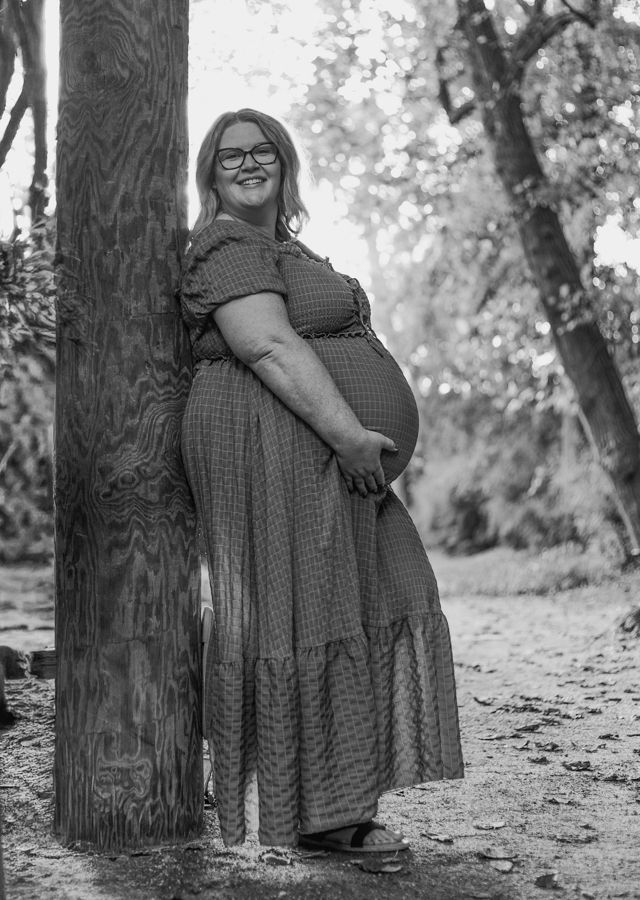 Pregnant woman leaning against a tree on a walk way maymont park rva
