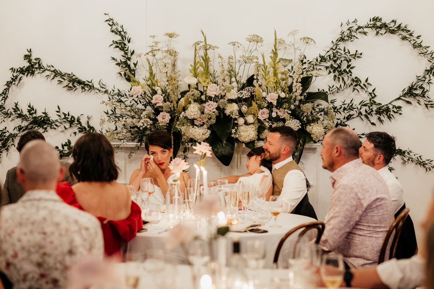 Wedding reception guests seated at long tables decorated with florals and candlelight at Rose and Smith captured by August and Vine